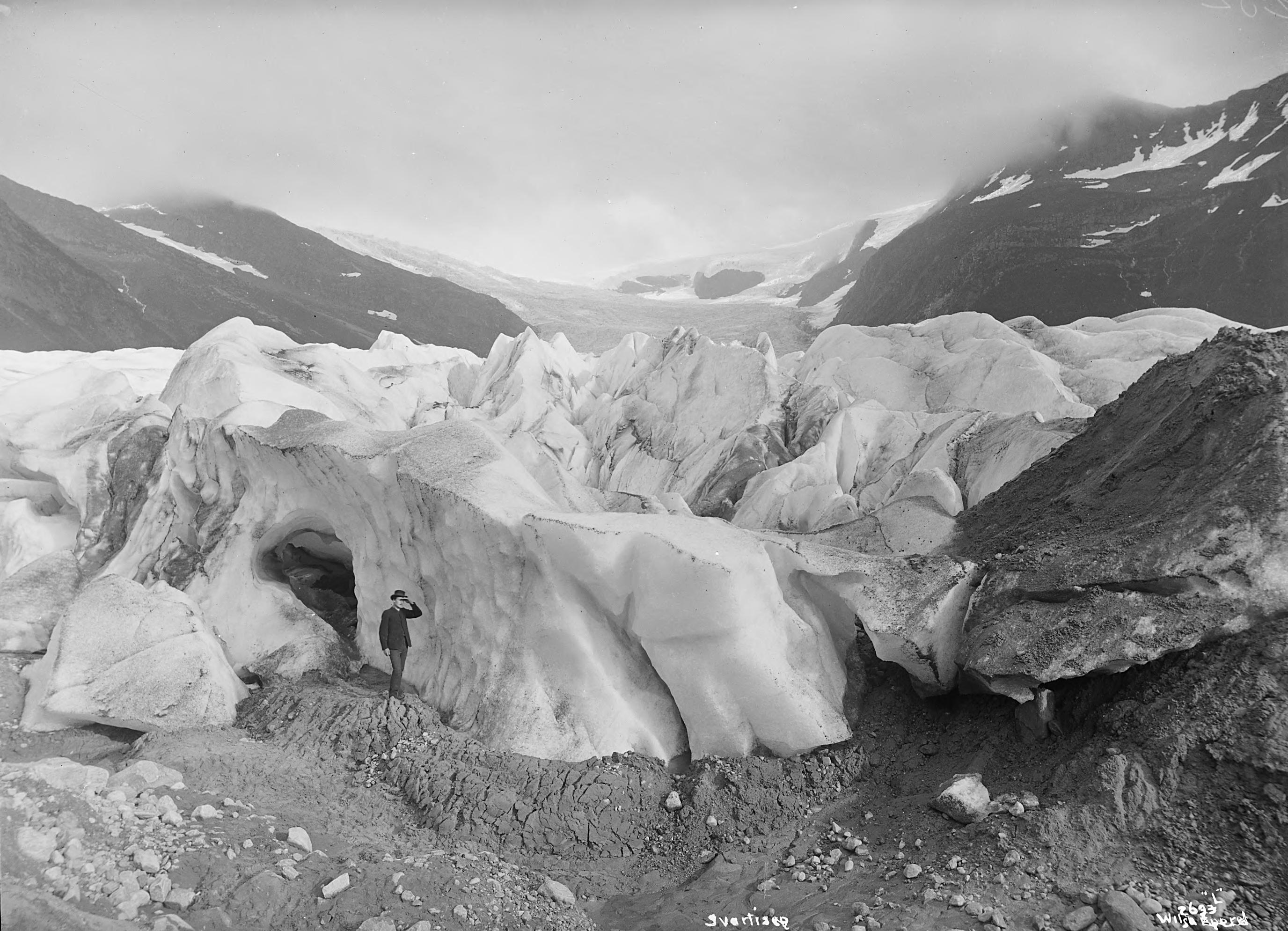 Svartkledd mann står foran et parti av Svartisen.