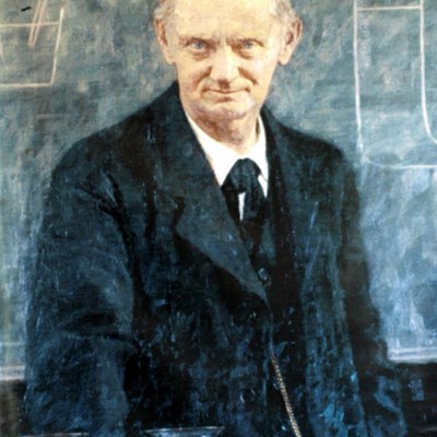 Maleri av en mannlig lærer i dress og slips foran en skoletavle.