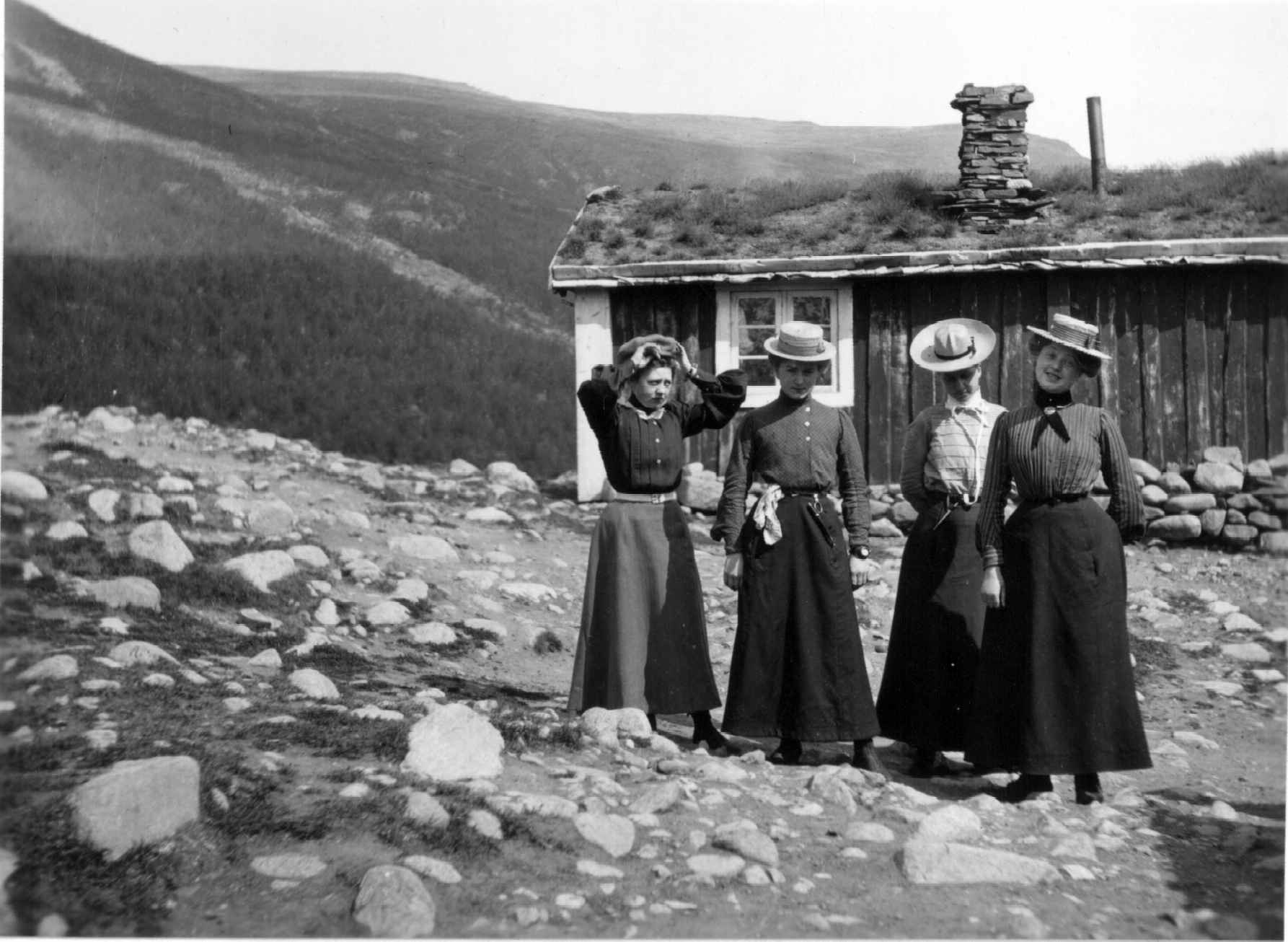 Fire kvinner i turdrakter med skjørt og hatt