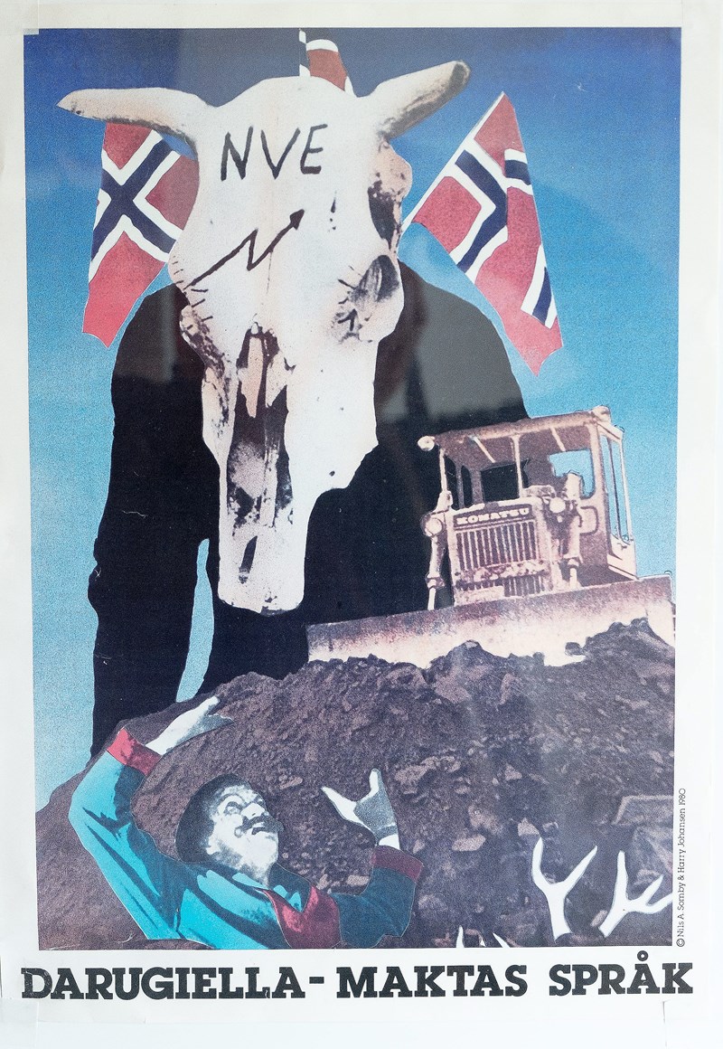 Plakat "Darugiella - Maktas språk" - Illustrativt at Samby begraves i jord med bulldoser, med en person med en hodeskalle fra rein med påskriften NVE og med norske flagg hengende på ryggen