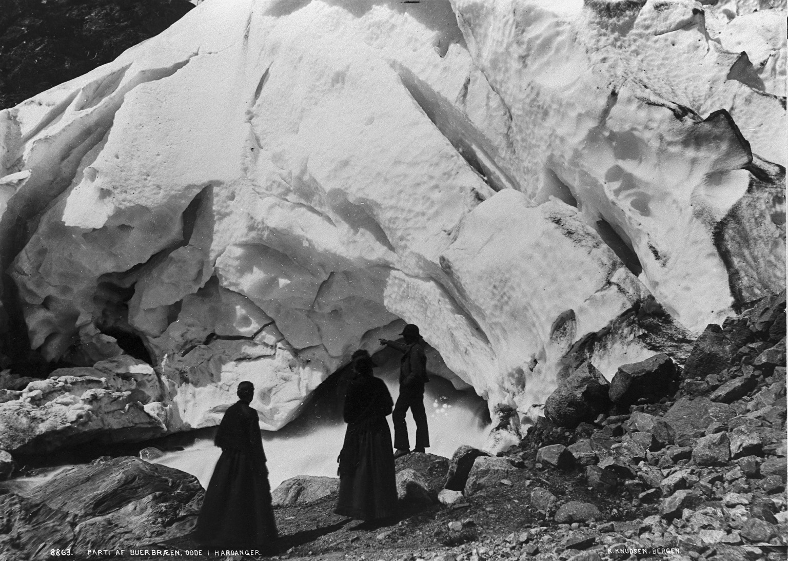 To kvinner og en mann står under breen.