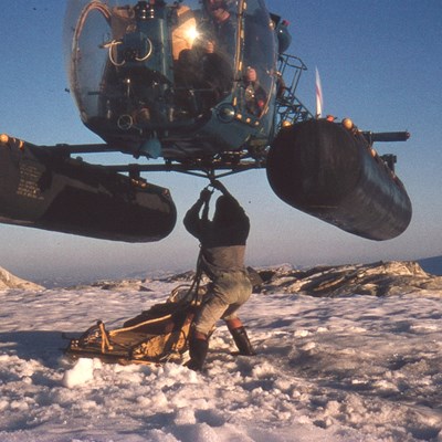 Mann fester last under flygende helikopter