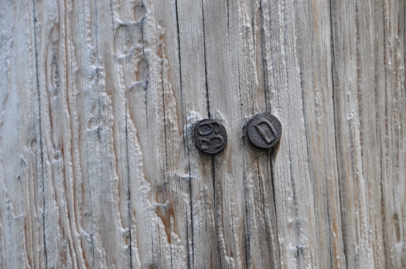 Små merker i jern på kraftmast i tre, merkene viser 39 og D