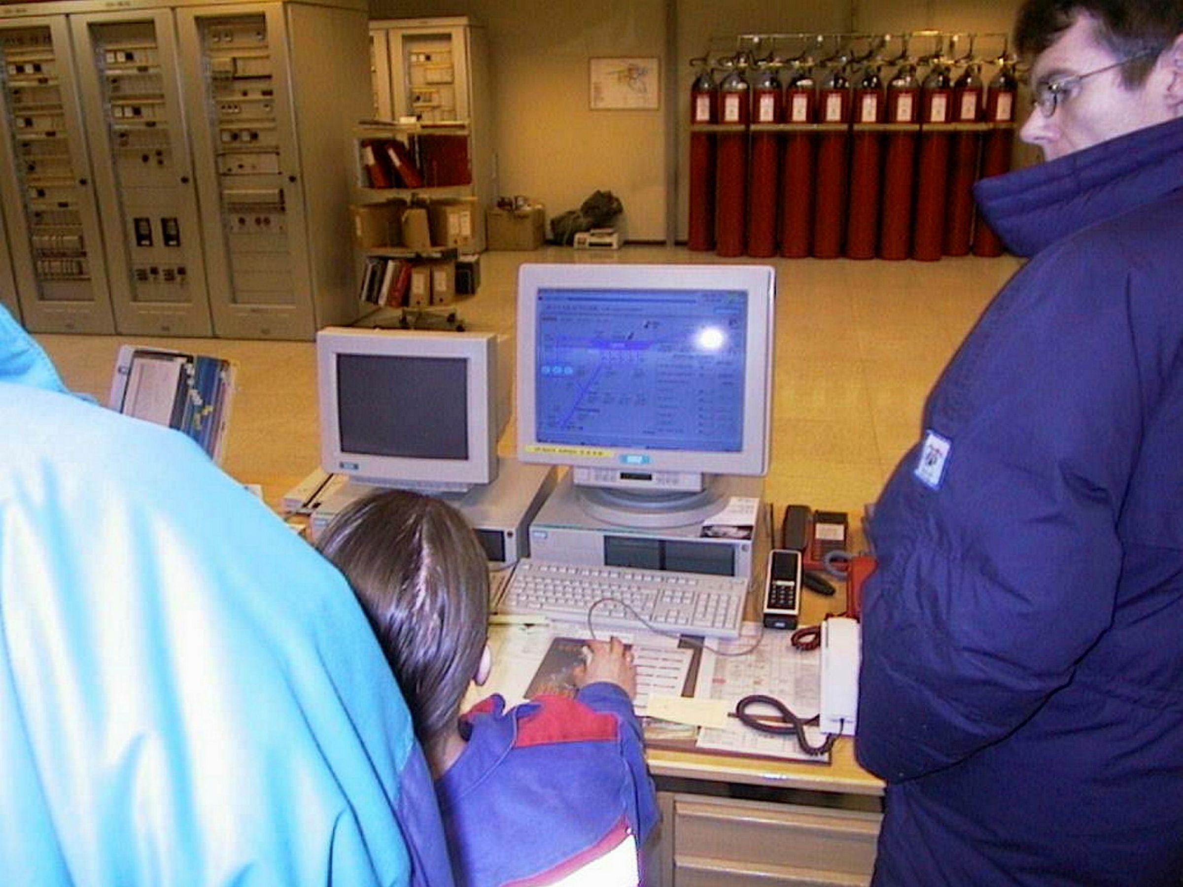 Mennesker står ved eldre datamaskin.