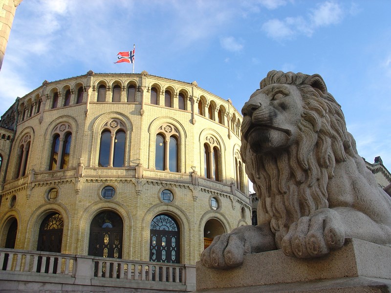 Stortingsbygningen med statue av løve i forgrunnen