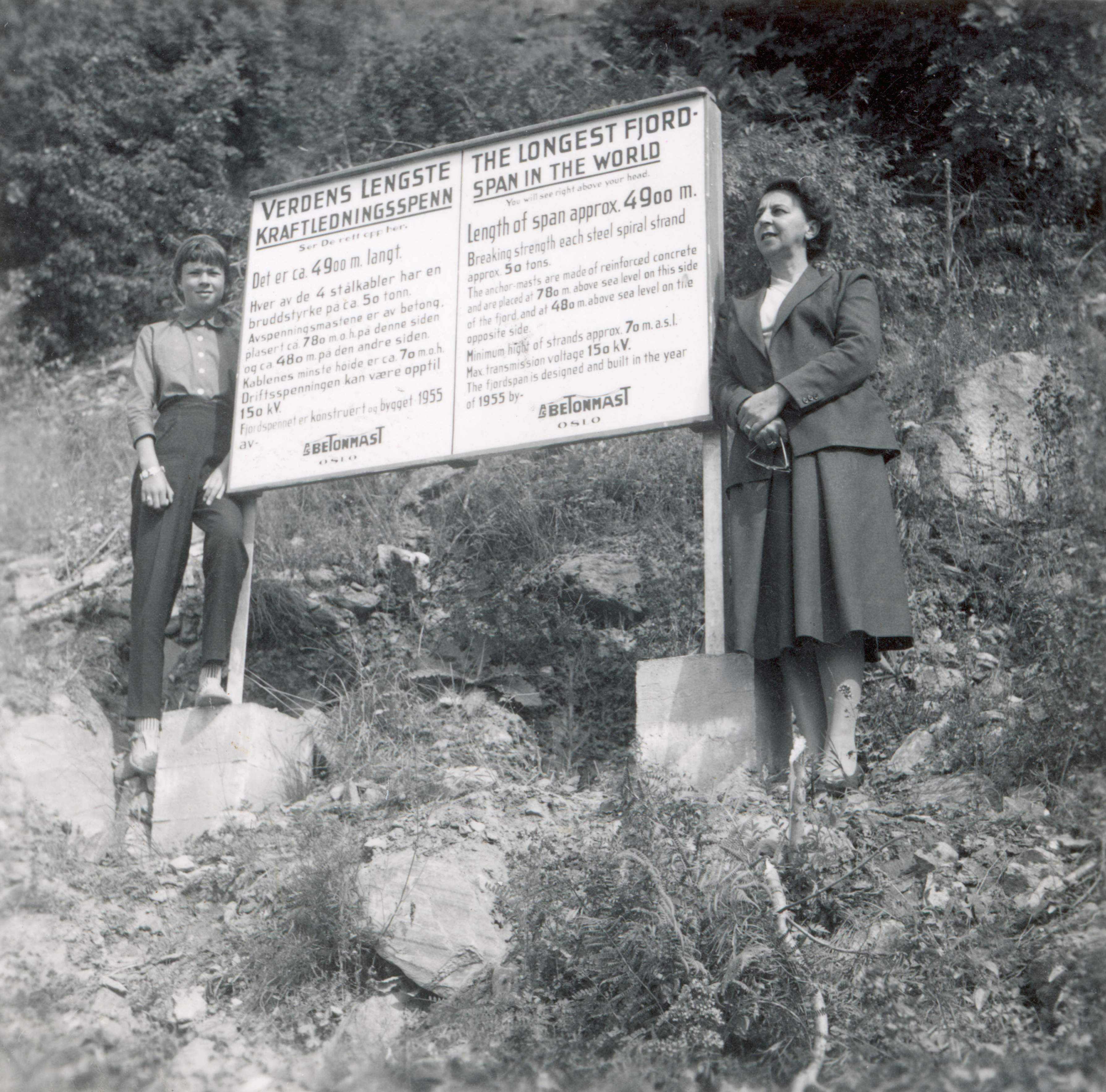 To kvinner står på hver side av et opplysningsskilt