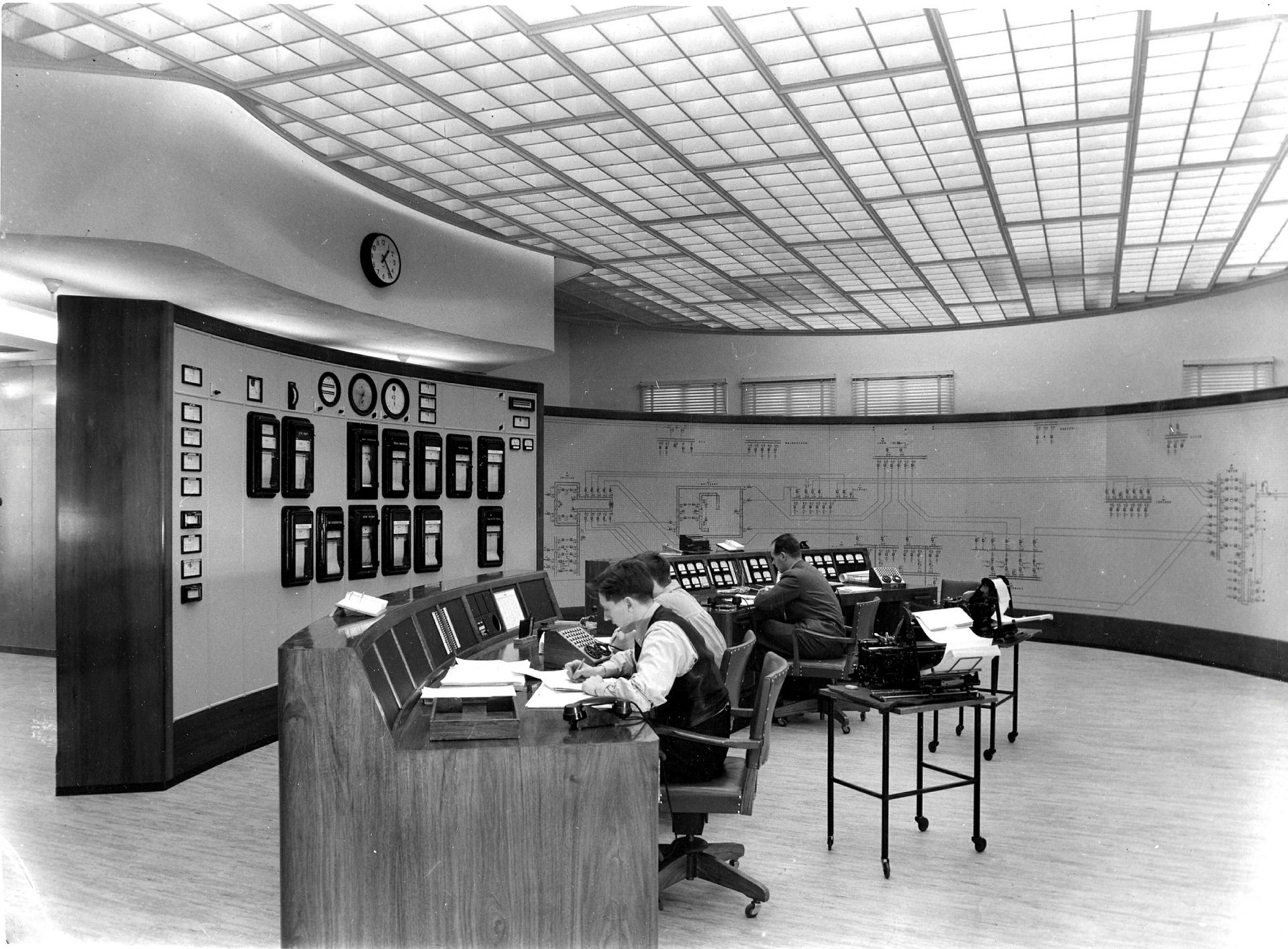 Menn sitter ved et kontrollbord og jobber