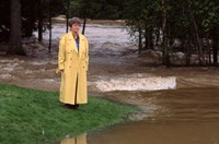 Kvinne i gul kåpe ser på elv. 