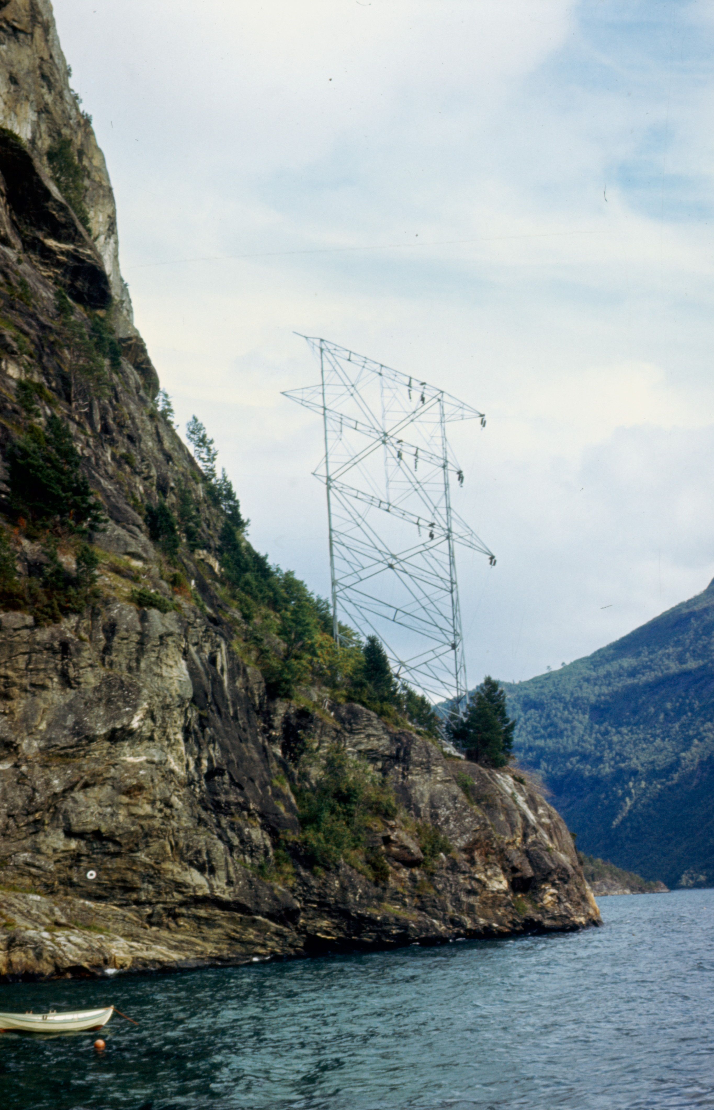 Kraftmast i bratt terreng ved sjø