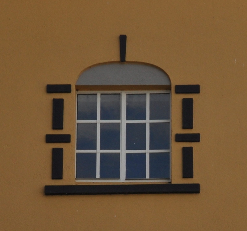 Rutete vindu på gulmalt fasade. 