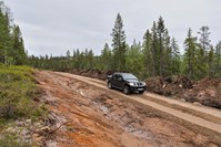 Bil som kjører på en ny skogsbilvei hvor vegetasjonen ikke har kommet tilbake langs kanten av veien. 