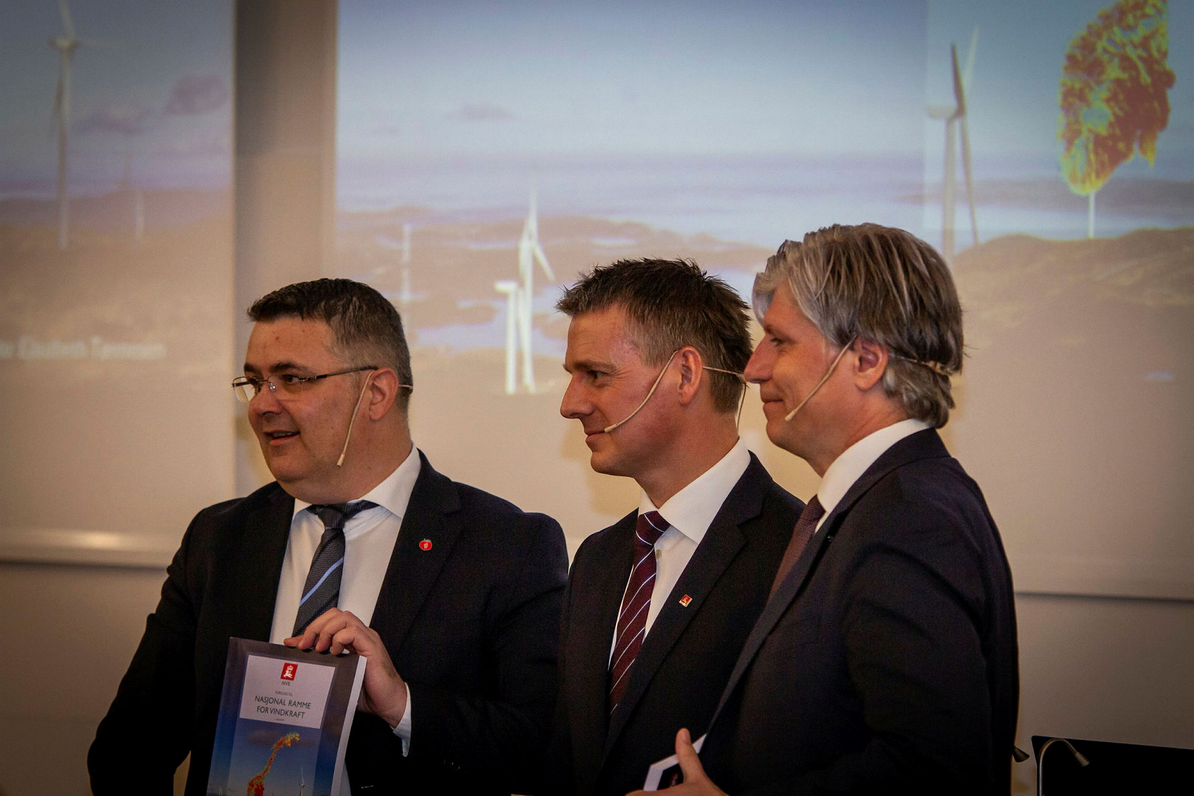 Tre menn holder en rapport