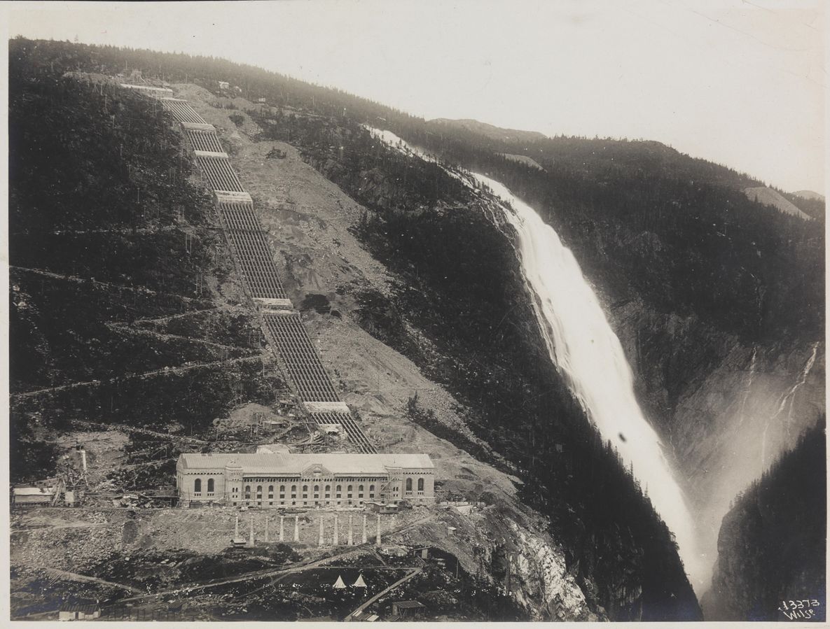 Et fjell med en foss og et stort murbygg