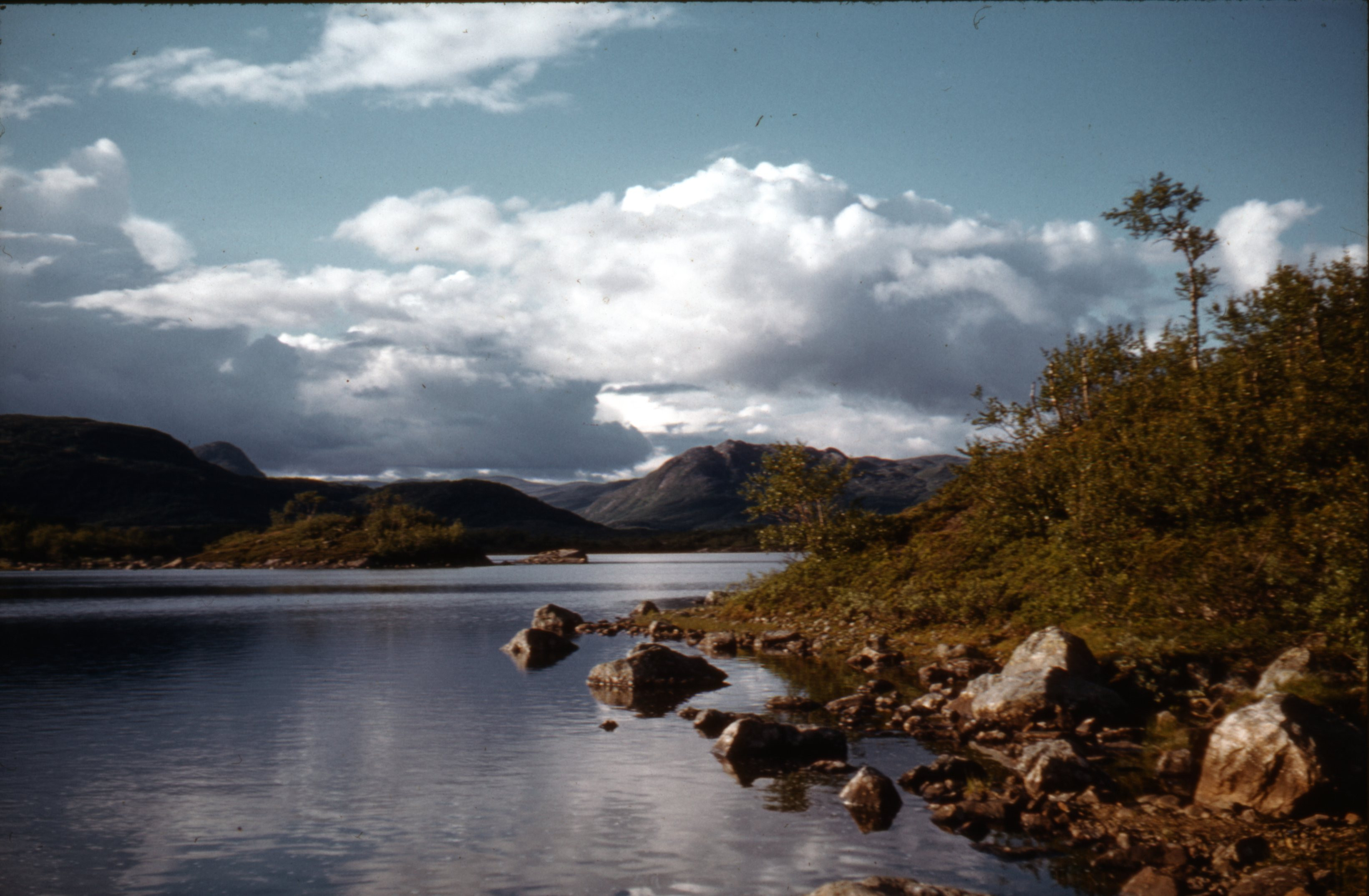 Landskap med innsjø, åser og fjell. 