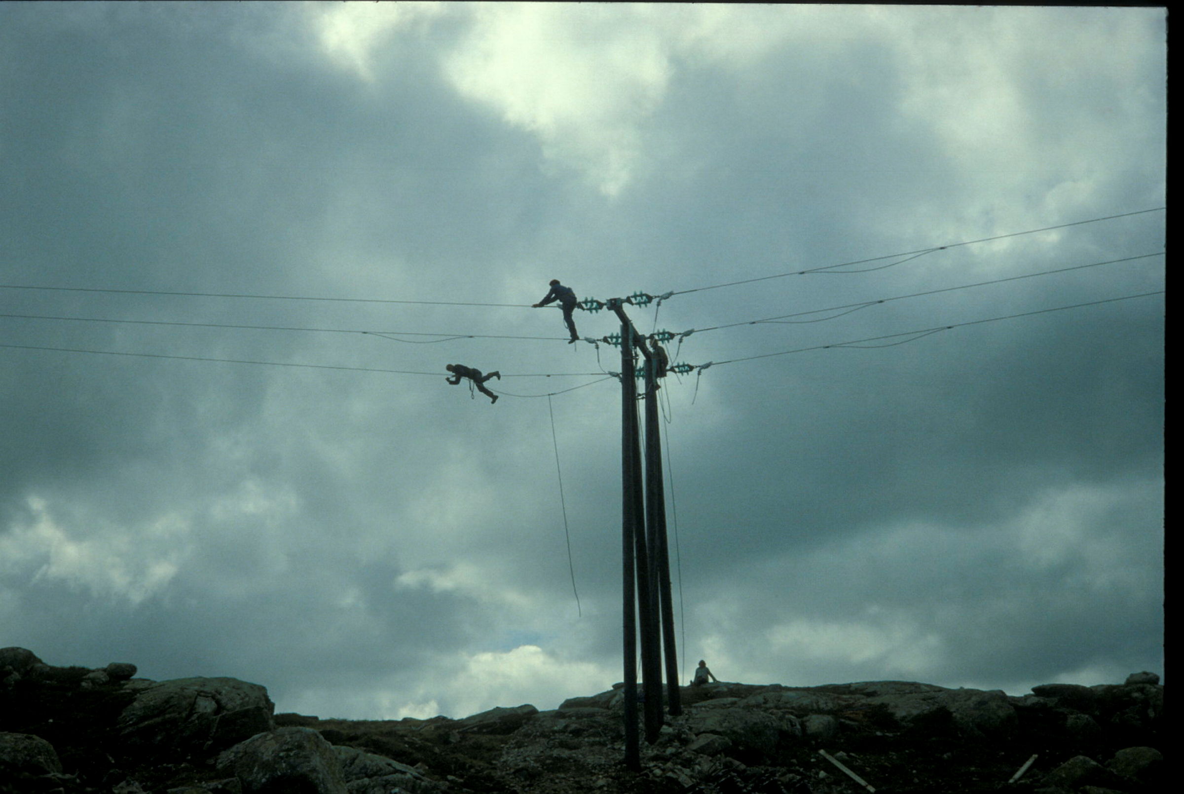 To menn ligger og arbeider på en kraftledning