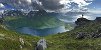 Bilde av norsk kystlandskap. Et menneske ser ut over et vann, fjellandskap og kyst med øyer. 