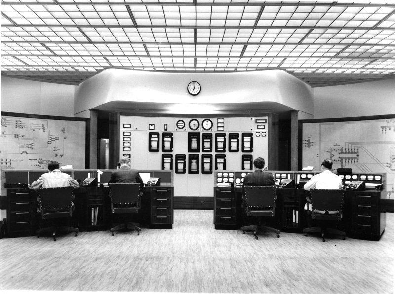 Flere menn sitter ved instrumenter i kontrollrom. 