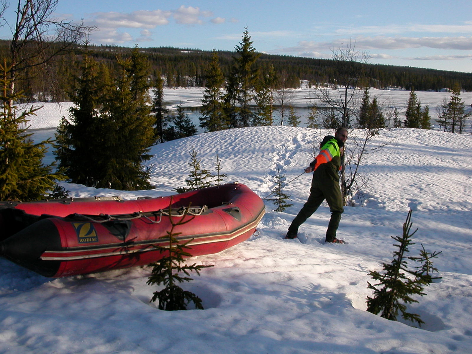 Mann som drar gummibåt gjennom snødekt landskap.