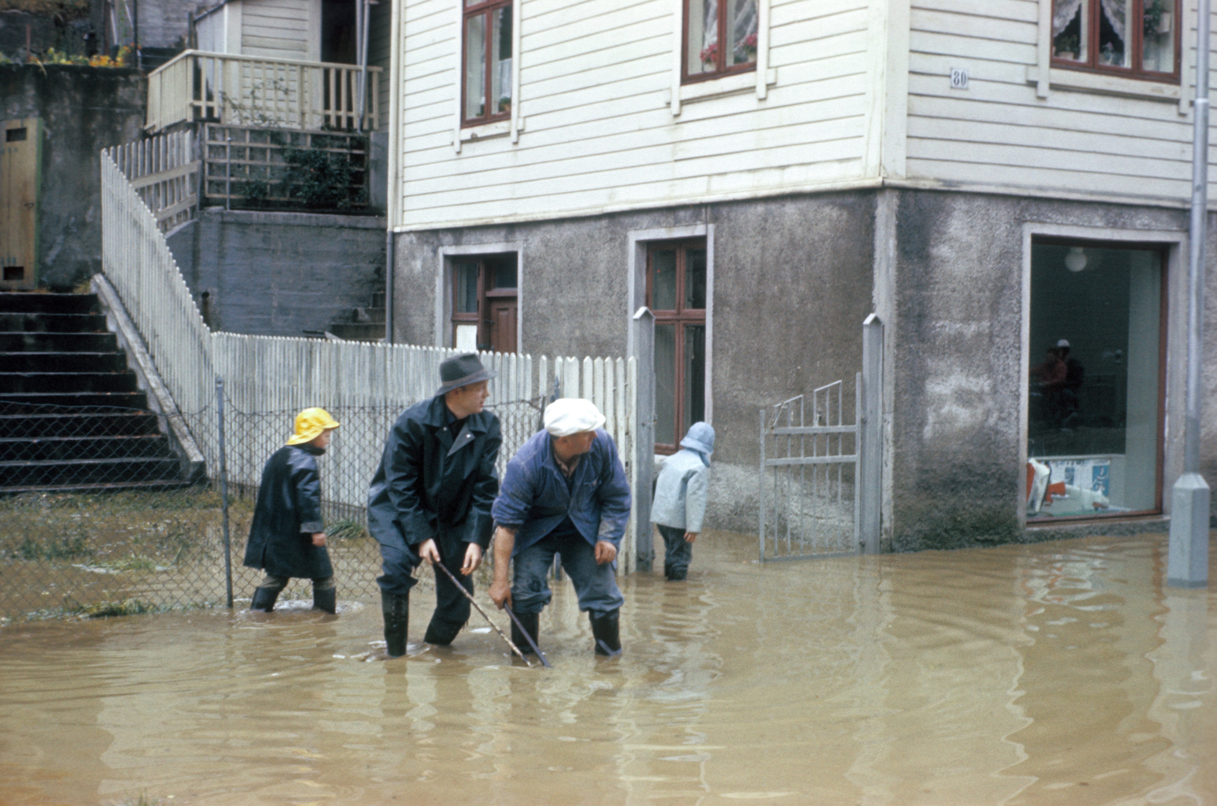 Mennesker ute i gate med høg vannstand etter flaum.