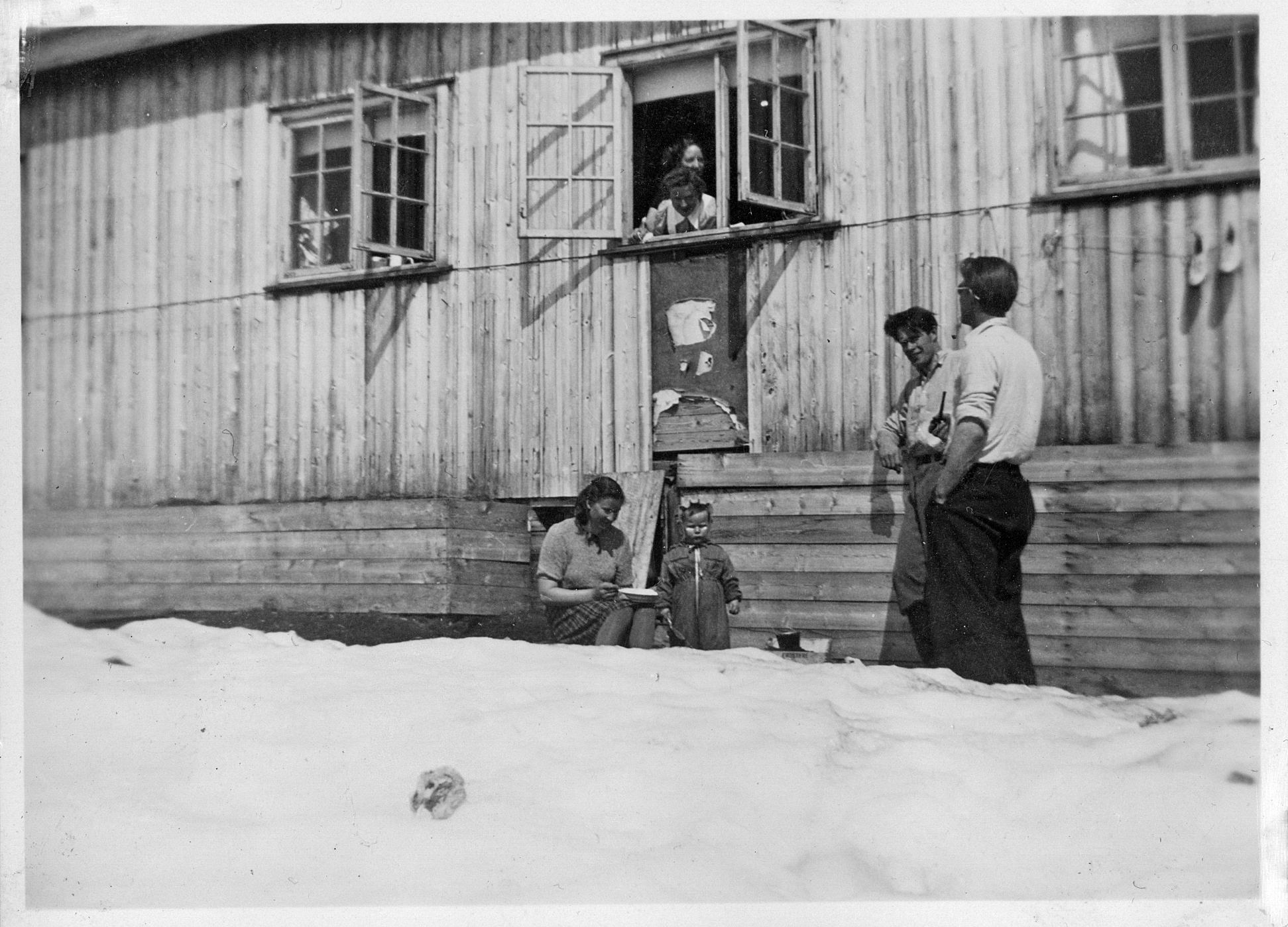 Anleggsfolk med familie framfor ei brakke.