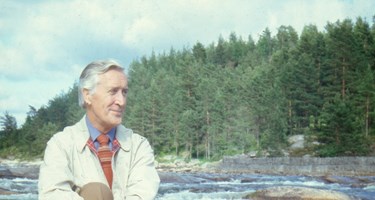 Sigmund Larsen sitter på en stein ved en elv.