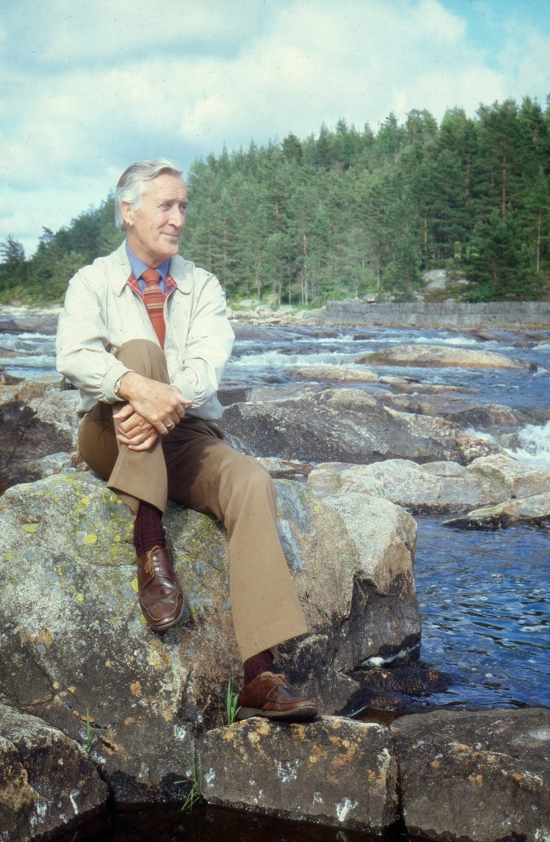 Sigmund Larsen sitter på en stein ved en elv.